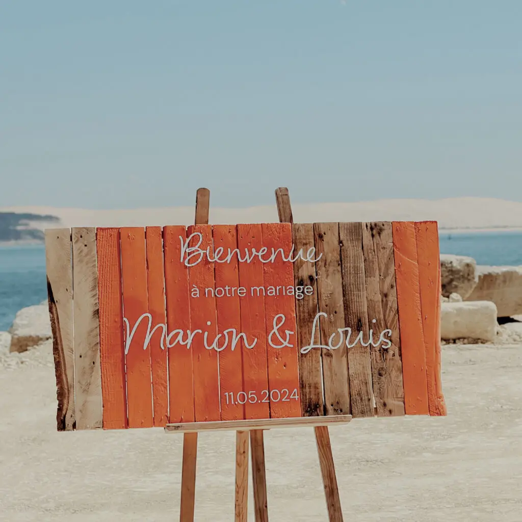 Panneau de bienvenue mariage avec des teintes terracotta et orangées, décor inspiré du Cap Ferret.